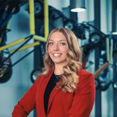 Bethany Slone featured standing in IAVS building wearing a red blazer.